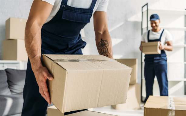Professional movers moving boxes inside a spacious room.
