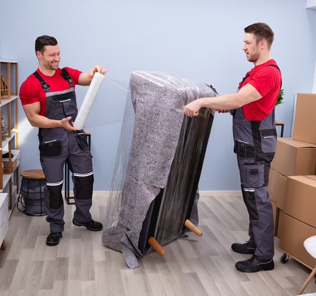 Professional movers carrying wrapped furniture together.