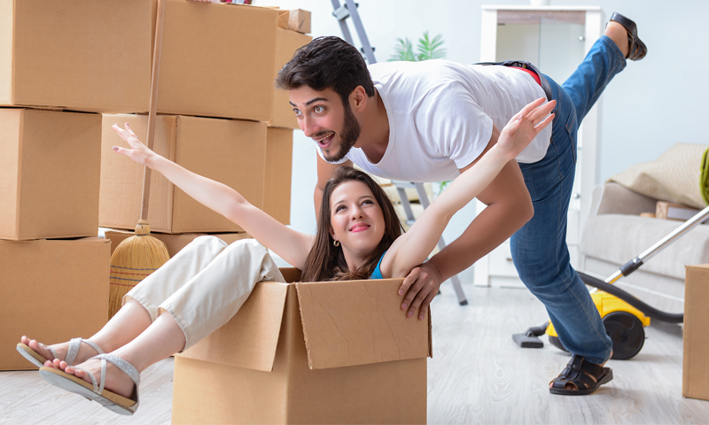 Couple playing inside a cardboard box after moving.