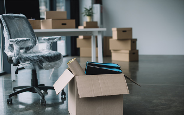 Office chair beside moving boxes in a workspace.