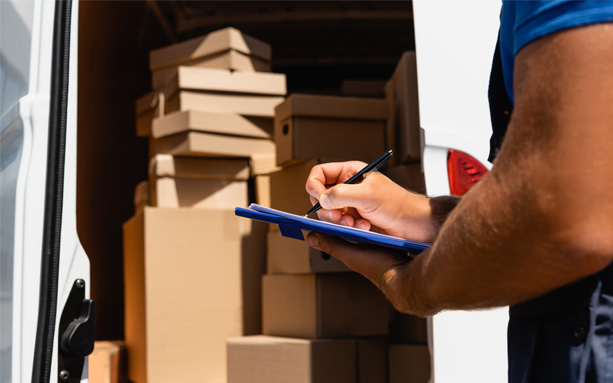 Professional mover writing on a clipboard beside a moving van.