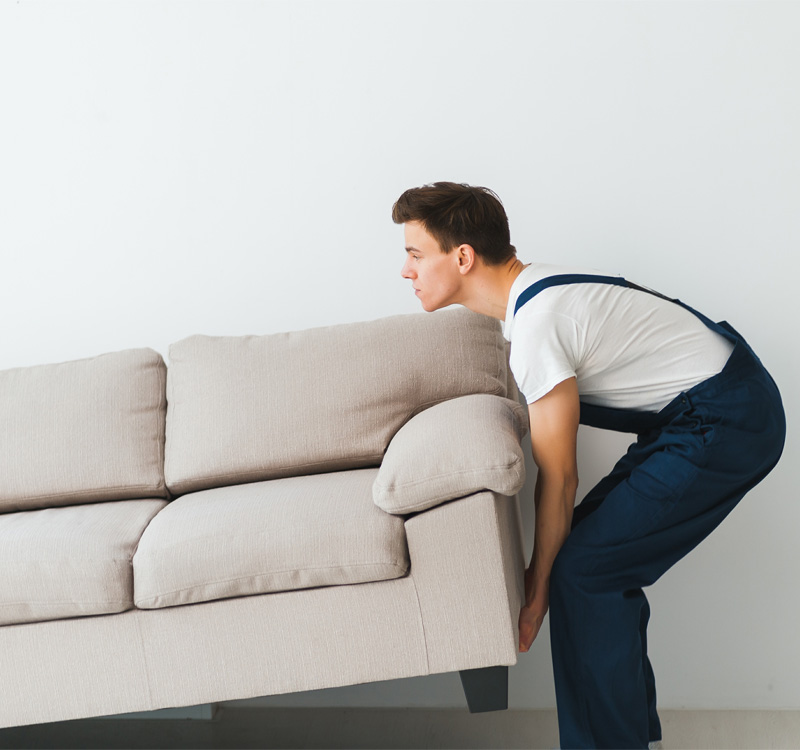Professional mover lifting a sofa inside a home.