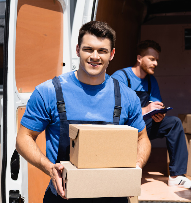 Professional movers carrying a moving box inside a home.