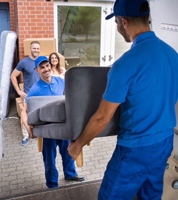 Professional movers unloading a sofa while homeowners watch.