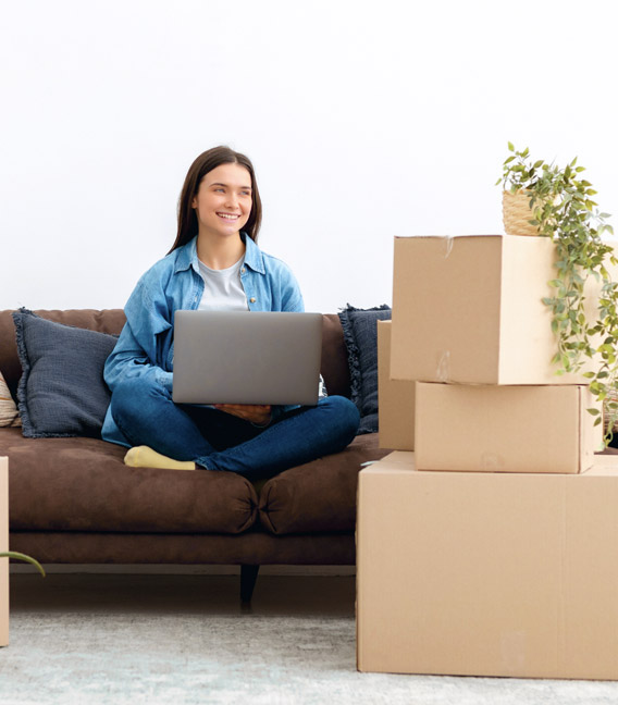 Homeowner using a laptop among moving boxes after a move.