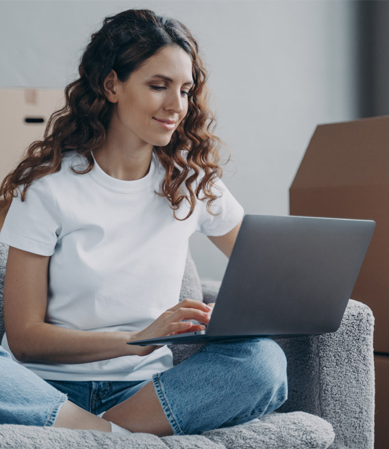 Woman using a laptop on a living room couch.