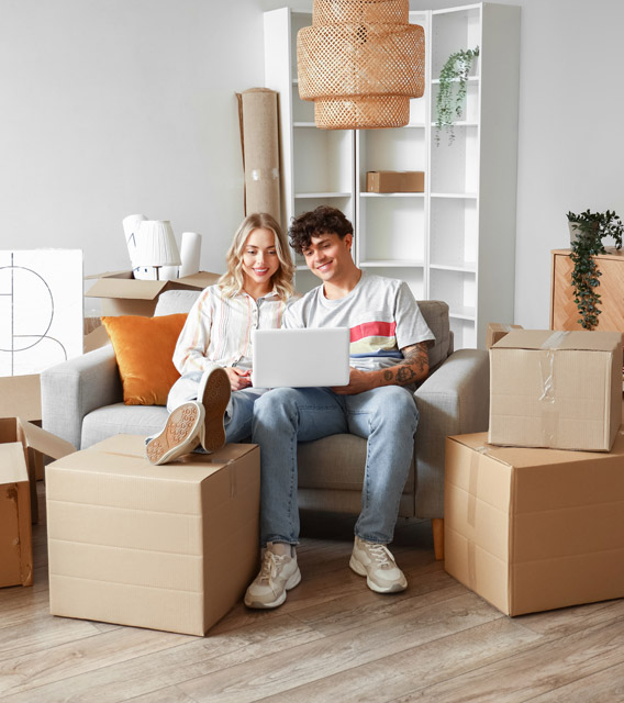 Happy couple sitting among moving boxes after a move.