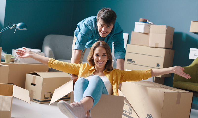 Happy couple celebrating their move while surrounded by moving boxes.