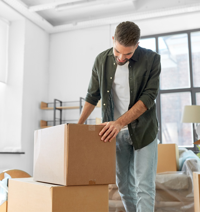 Professional mover carrying moving boxes into a room.
