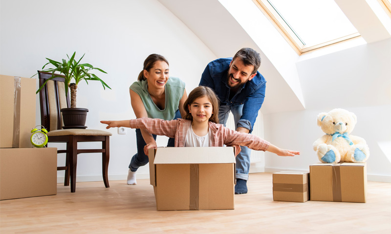 Happy family carrying moving boxes into a new home.