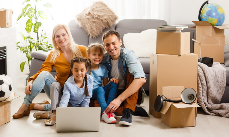 Family using a laptop among moving boxes.