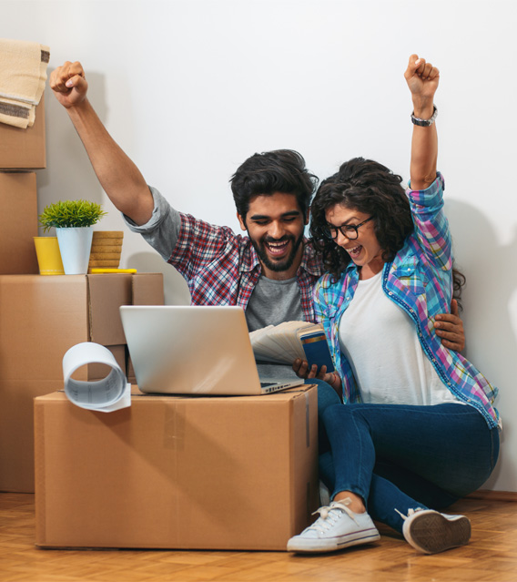 Happy couple celebrating a successful move with packed boxes.