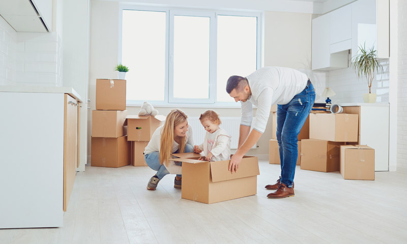 Happy family posing in their new home with moving boxes.