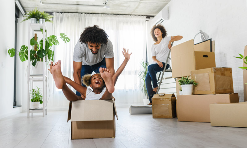 Happy family carrying moving boxes into their new home.
