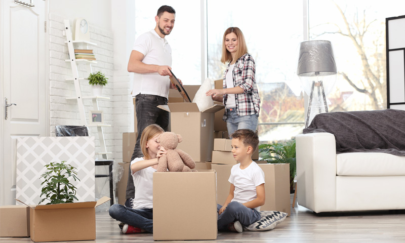 Happy family carrying moving boxes into a new home.