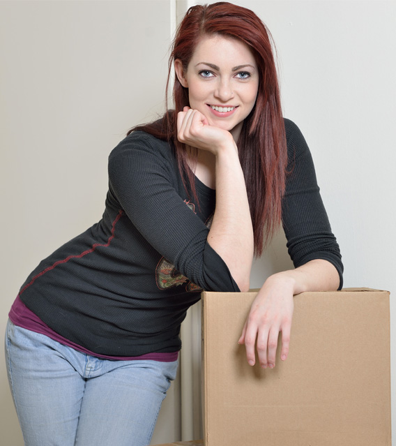 Happy homeowner holding a moving box in a new home.