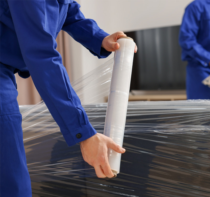 Professional movers wrapping furniture for moving.