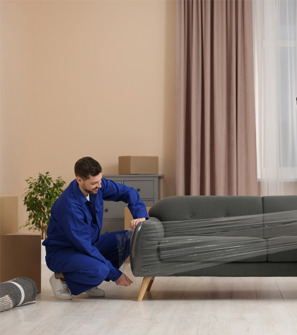 Professional mover lifting a sofa inside a living room.